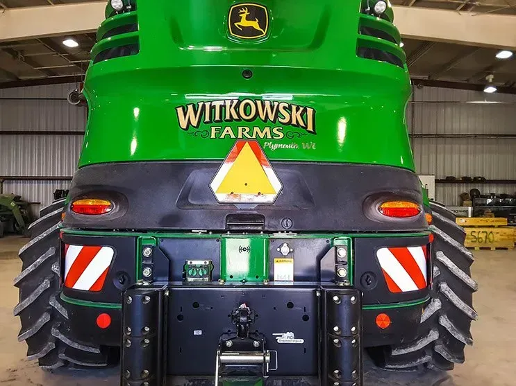 A green john deere tractor is parked in a warehouse.