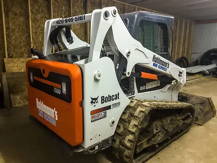 A bobcat track loader is parked in a garage.