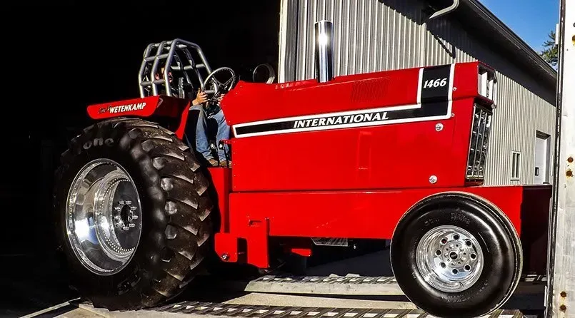 A red international tractor is parked in front of a building