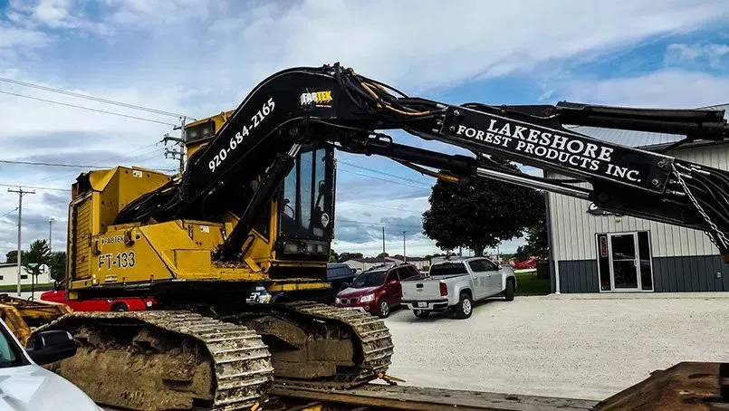 A large yellow excavator is parked in front of a building.
