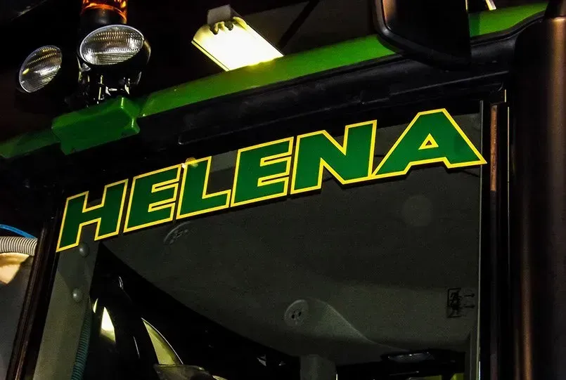 A green tractor with helena written on the windshield