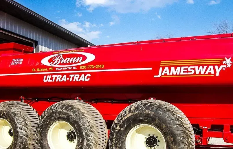 A red jamesway trailer is parked in front of a building