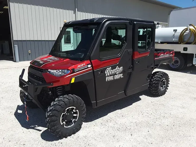 A red and black utility vehicle is parked in front of a building.