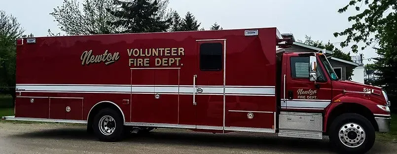 A red volunteer fire dept truck is parked in a parking lot