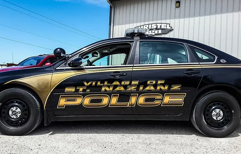 A black and gold police car is parked in front of a building