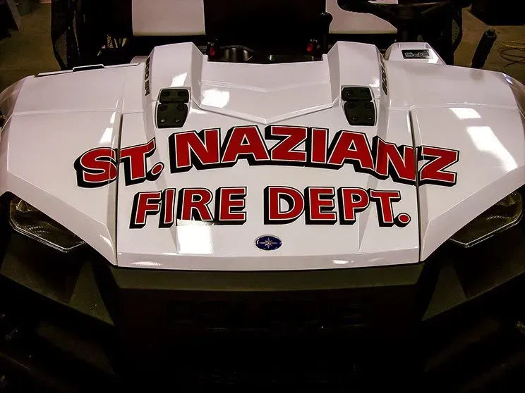 A white atv with st. nazianz fire dept written on the front