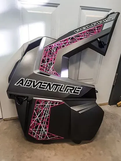 A black and pink motorcycle is sitting in front of a door.