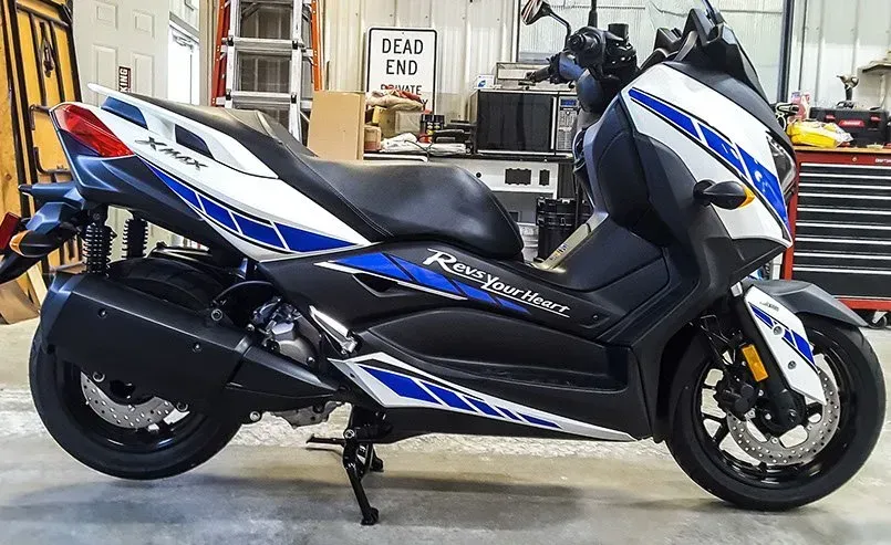 A blue and white scooter is parked in a garage.