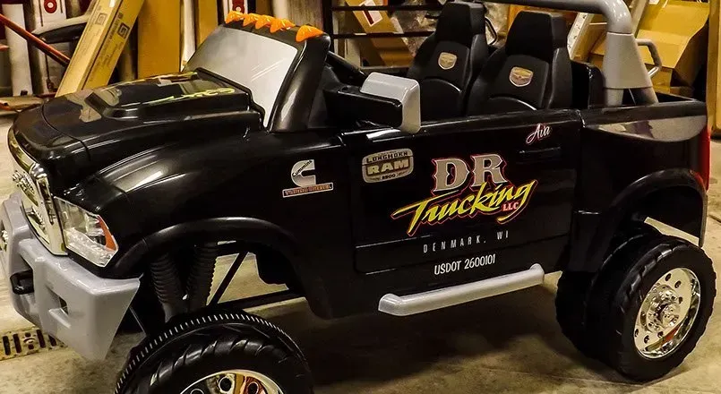 A black truck with dr trucking written on the side is parked in a garage.