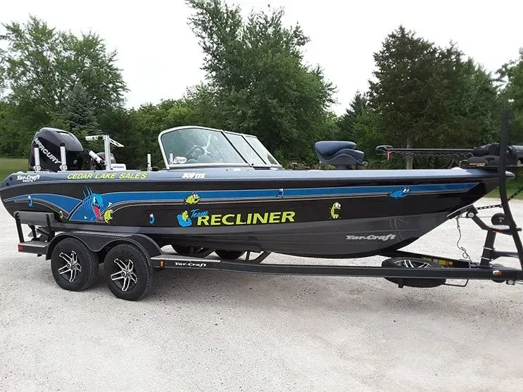 A black and blue fishing boat is parked on a trailer.