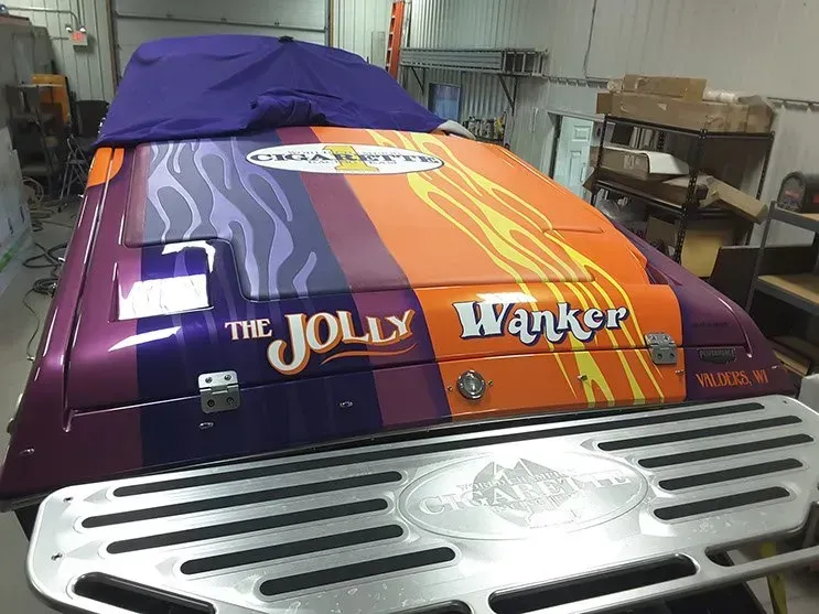 A purple and orange race car is sitting in a garage.