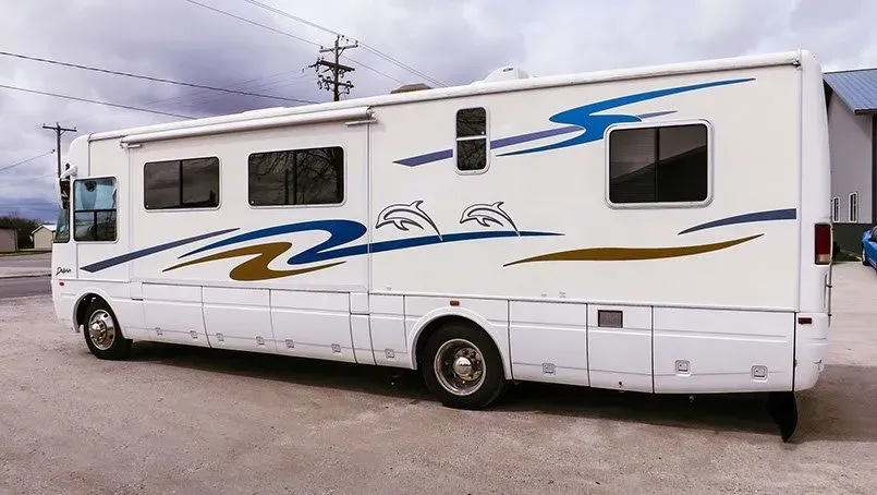 A large white rv is parked in a parking lot.
