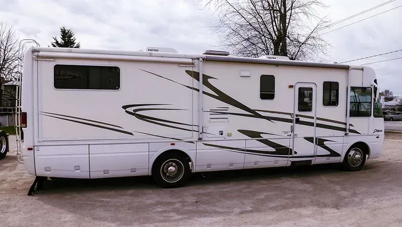 A large white rv is parked in a parking lot.