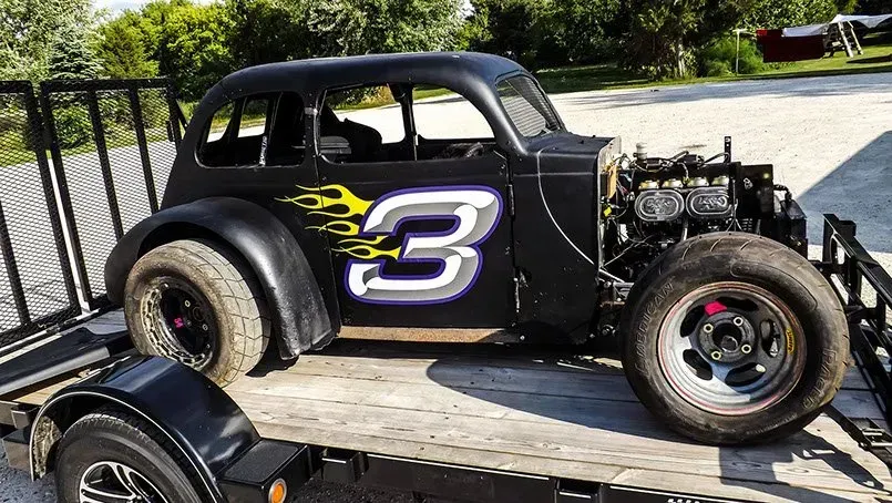 A black race car with the number 3 on the side is on a trailer.