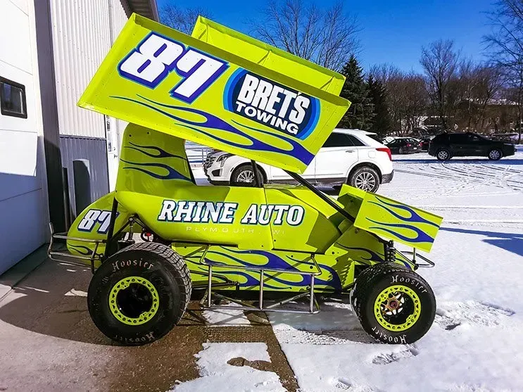 A yellow race car with the number 87 on it is parked in the snow.