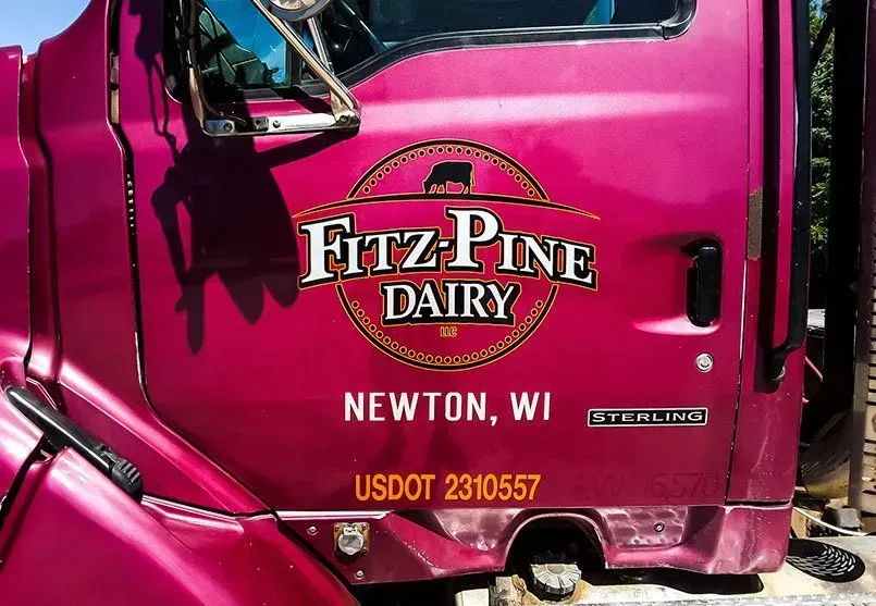 A pink fitz pine dairy truck is parked in newton wi