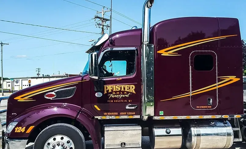 A purple semi truck is parked in a parking lot.