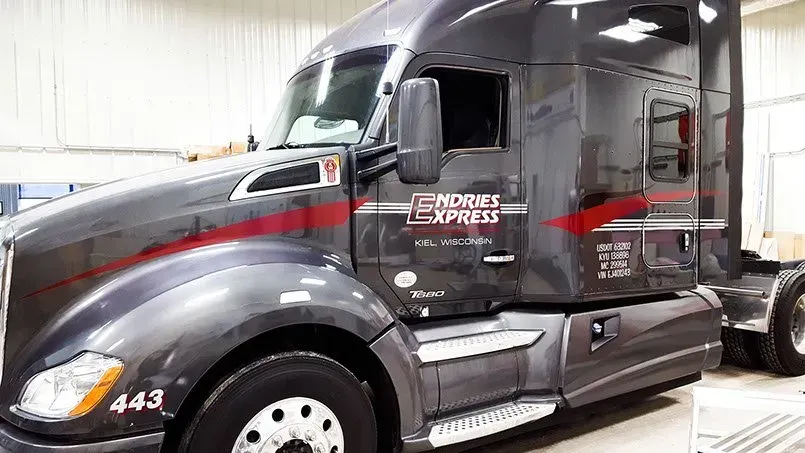 A black semi truck is parked in a garage.