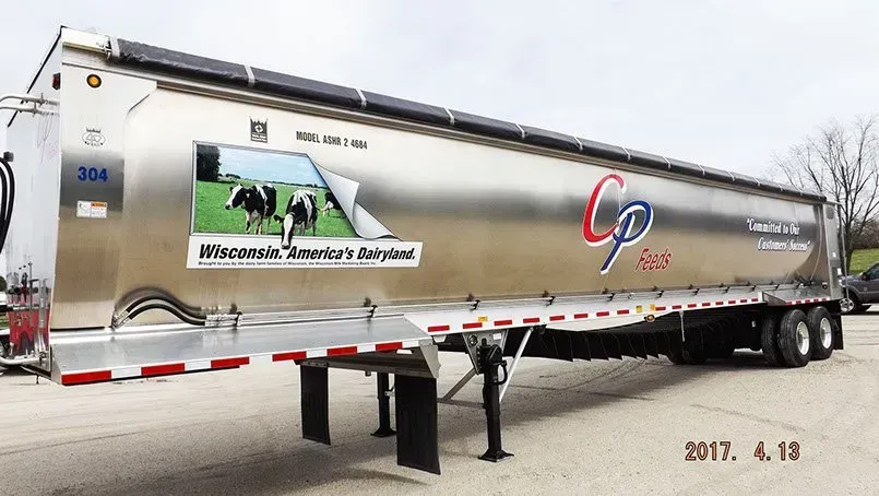 A semi truck with a cow on the side is parked in a parking lot.