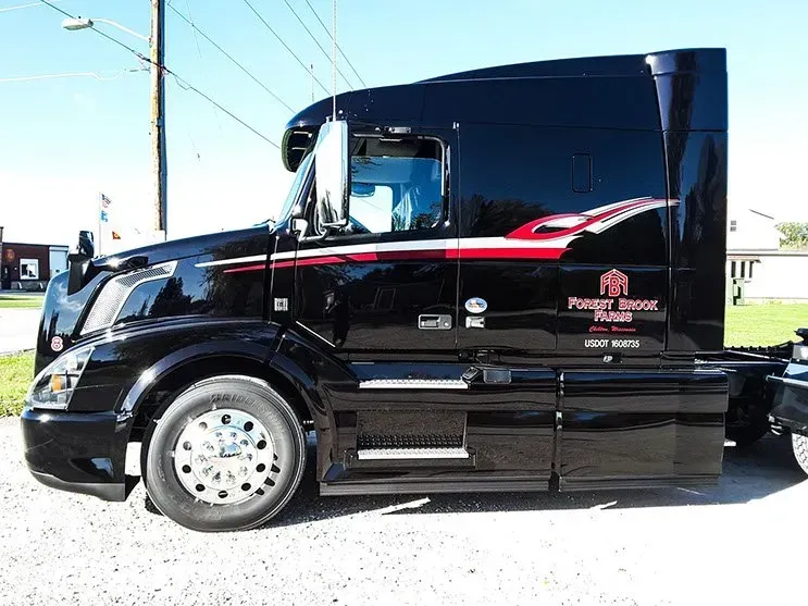 A black semi truck is parked on the side of the road.