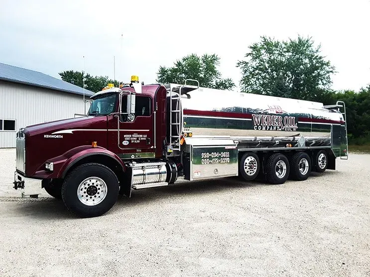 A large tanker truck is parked in a gravel lot.