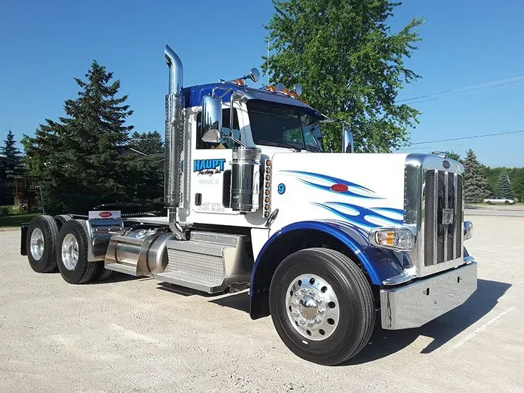 A white and blue semi truck is parked in a parking lot