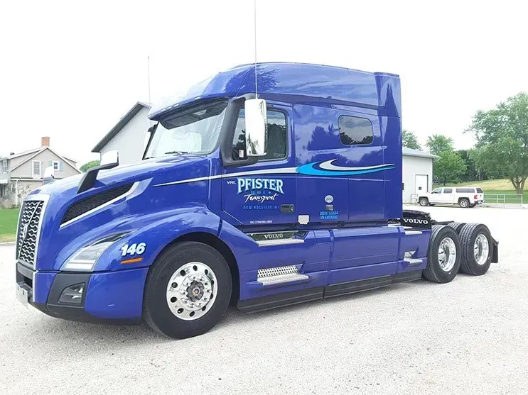 A blue semi truck is parked in a gravel lot.