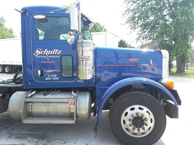 A blue schultz semi truck is parked in a parking lot