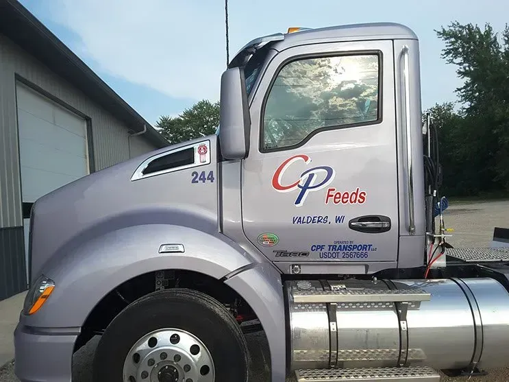A cp feeds truck is parked in front of a garage.