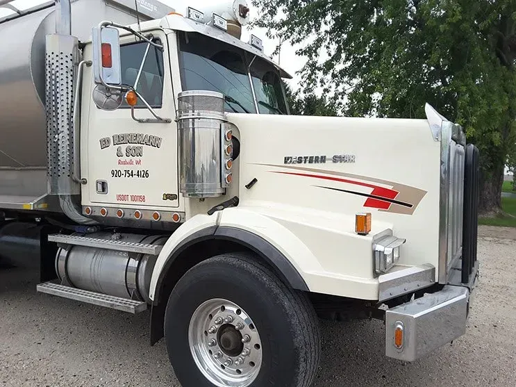A white semi truck is parked on the side of the road.