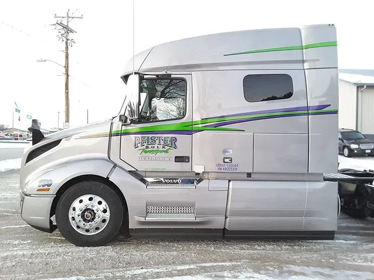 A large semi truck is parked in the snow in front of a building.