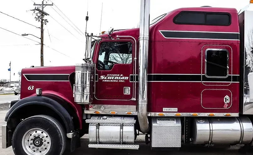 A red semi truck is parked on the side of the road.