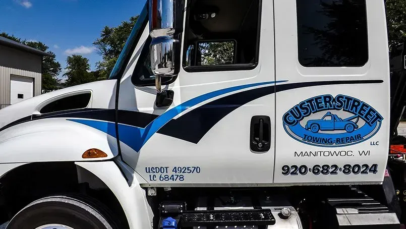A white truck with a blue stripe on the side is parked in front of a building.