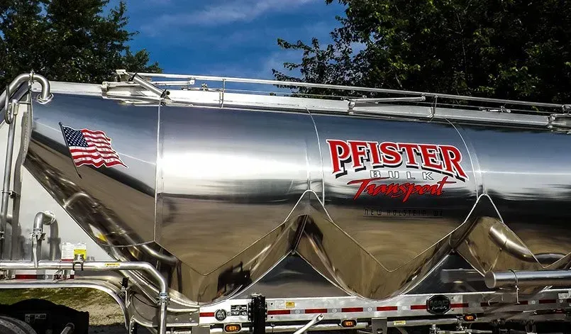 A silver truck with the word peister on the side is parked in front of a building.