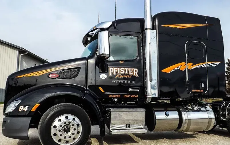 A black semi truck is parked in front of a building.