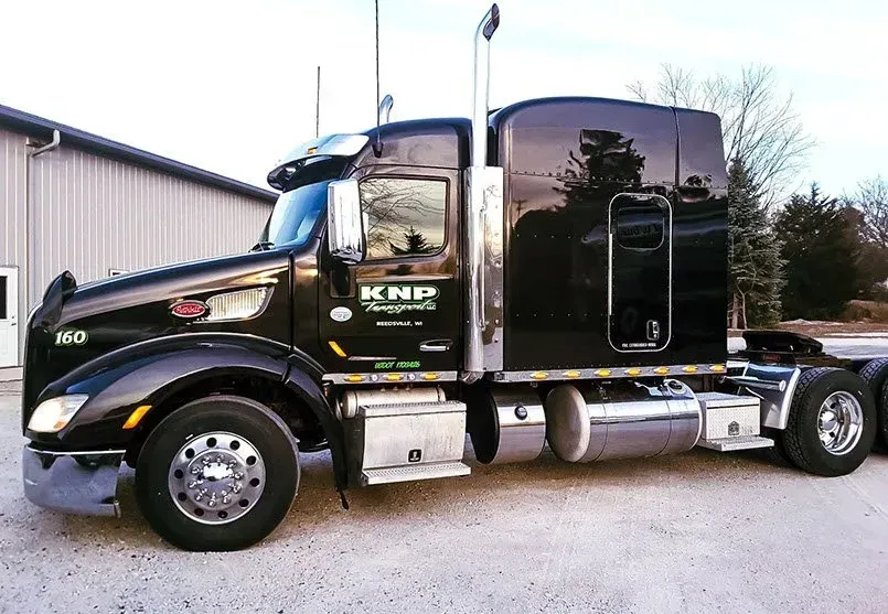 A black semi truck is parked in front of a building.
