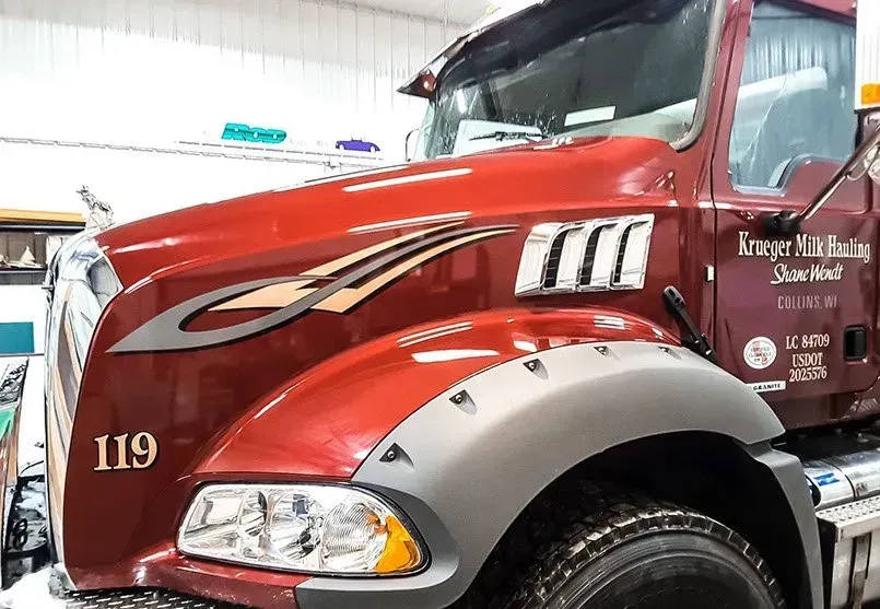A red truck with the number 119 on the front is parked in a garage.