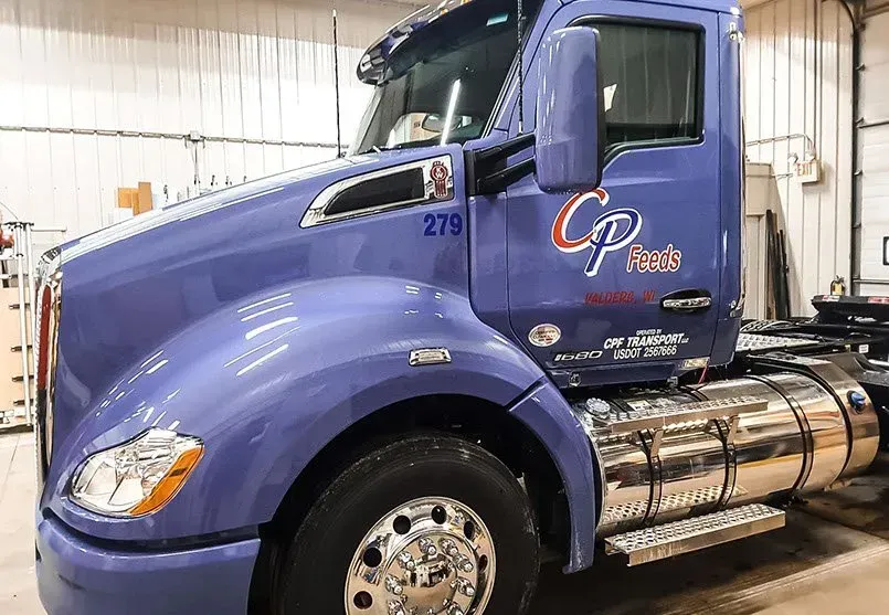 A purple semi truck is parked in a garage.