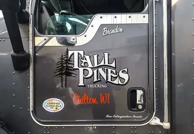 The side of a truck with a sticker on it that says tall pines.