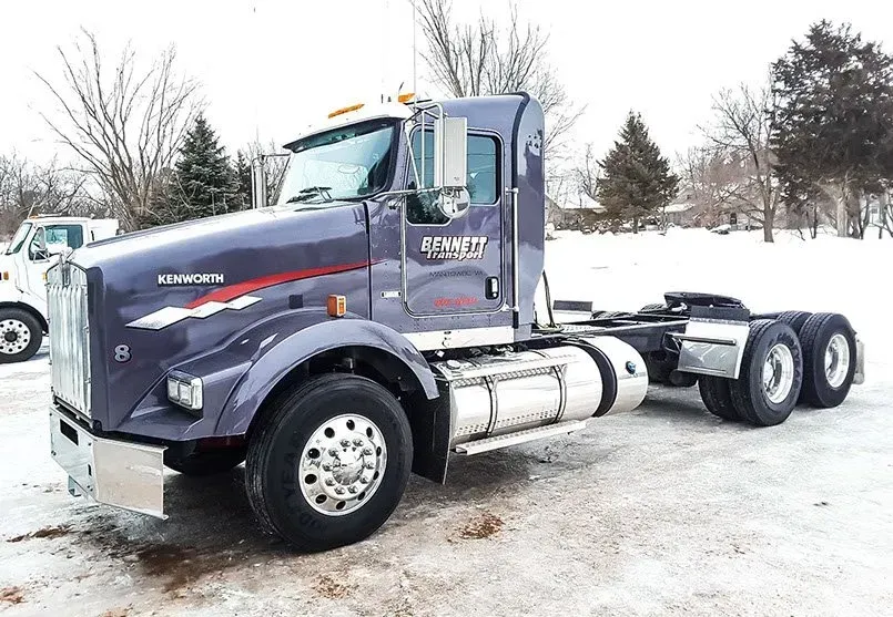 A kenworth semi truck with a trailer is parked in the snow.