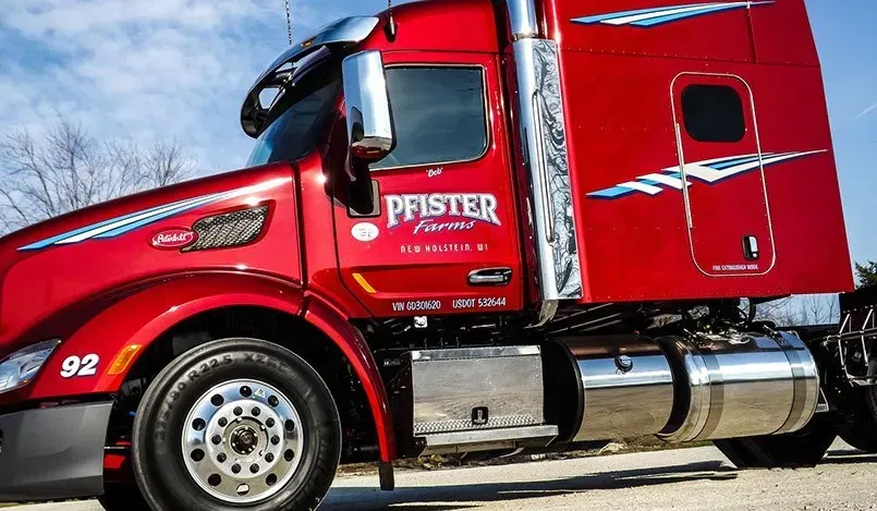 A red semi truck is parked on the side of the road.
