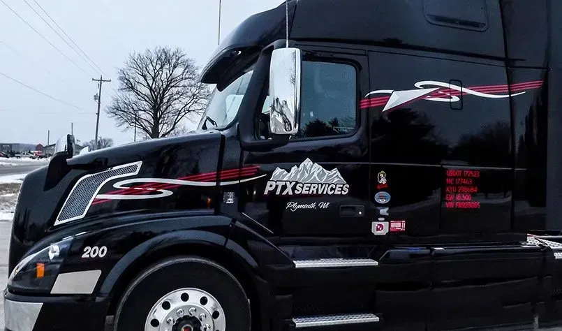 A black semi truck is parked on the side of the road.