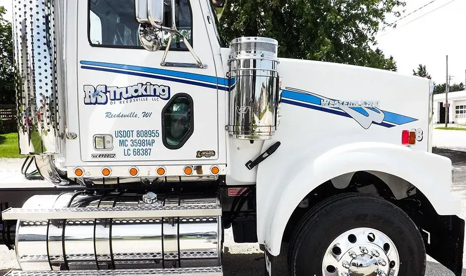 A white semi truck is parked on the side of the road.