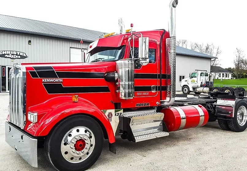 A red semi truck is parked in front of a building.