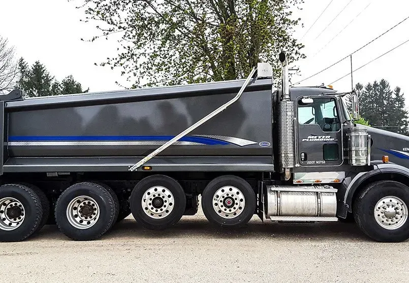 A dump truck is parked in a gravel lot