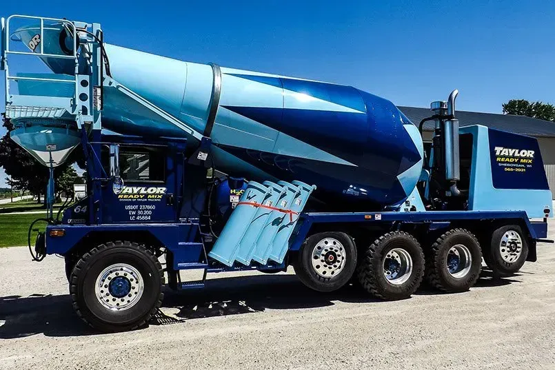 A taylor concrete mixer truck is parked in a gravel lot