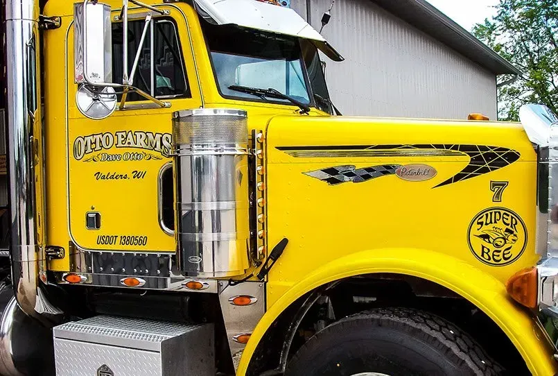 A yellow semi truck is parked in front of a building