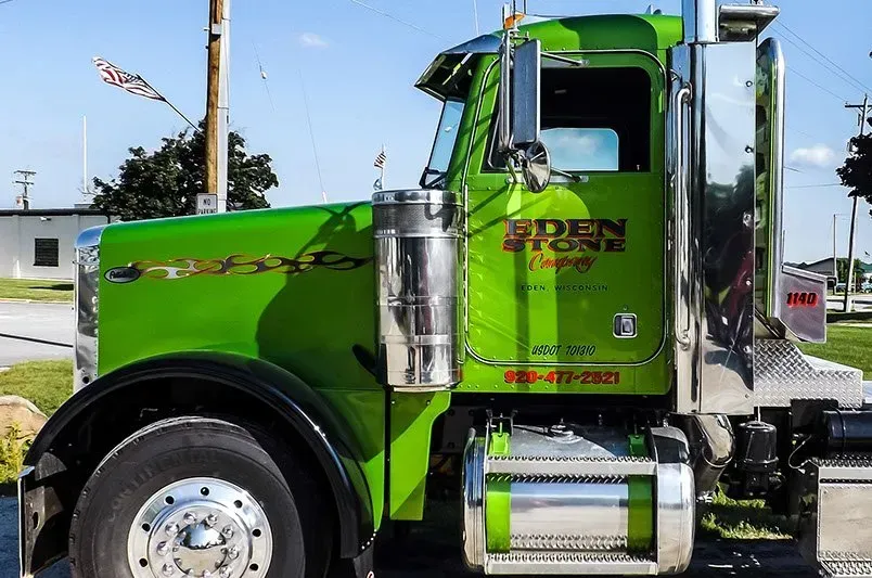 A green semi truck is parked on the side of the road