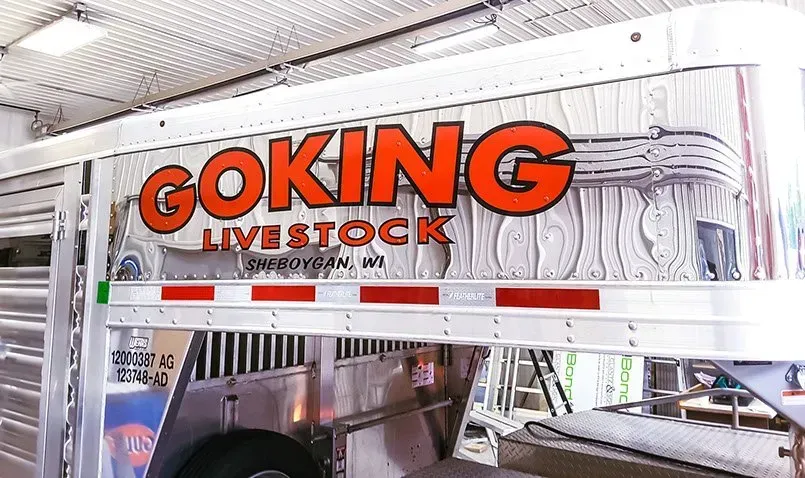 A goking livestock trailer is parked in a garage.