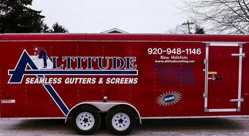 A red trailer that says altitude seamless gutters and screens